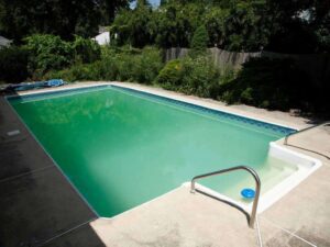 Piscina con agua verde causada por algas antes del tratamiento profesional